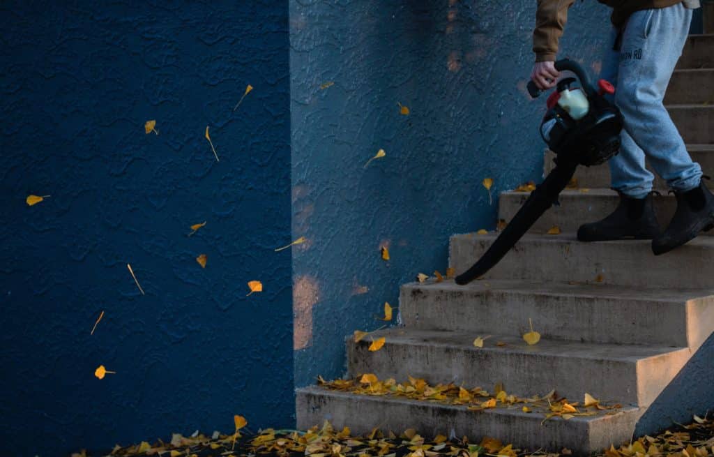 man blowing leaves off stairs