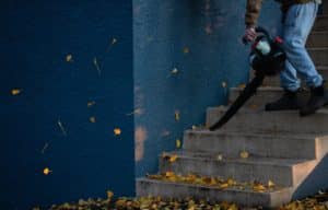 man blowing leaves off stairs