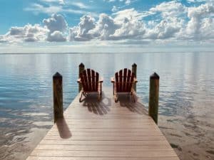 dock with two Adirondack chairs over water